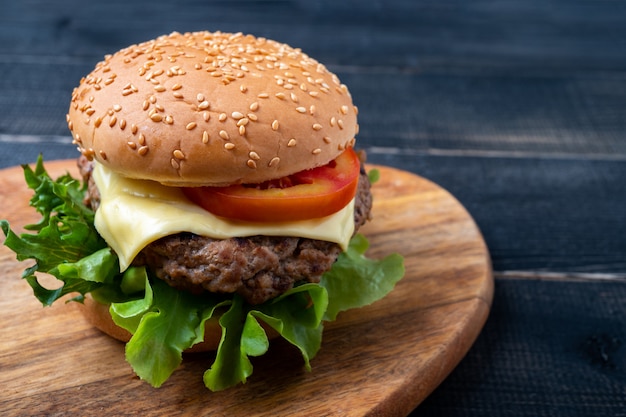 Verse smakelijke zelfgemaakte hamburger met verse groenten, sla, tomaat, kaas op een snijplank.