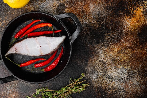 Verse steak rauwe vis heilbot set, met ingrediënten en rozemarijn kruiden, op oude donkere rustieke tafel achtergrond, bovenaanzicht plat lag, met kopie ruimte voor tekst