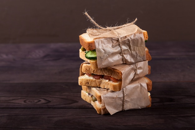 Verse toast met zalm, roomkaas en groenten liggen op een stapel, gewikkeld in knutselpapier.