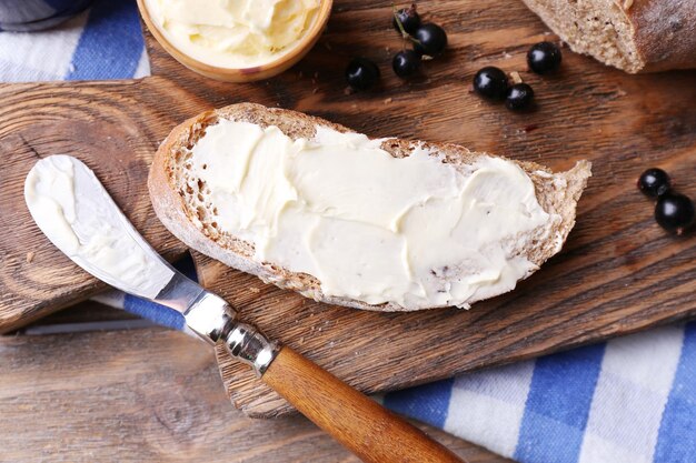 Foto verse toast met zelfgemaakte boter en zwarte bessenjam op houten ondergrond