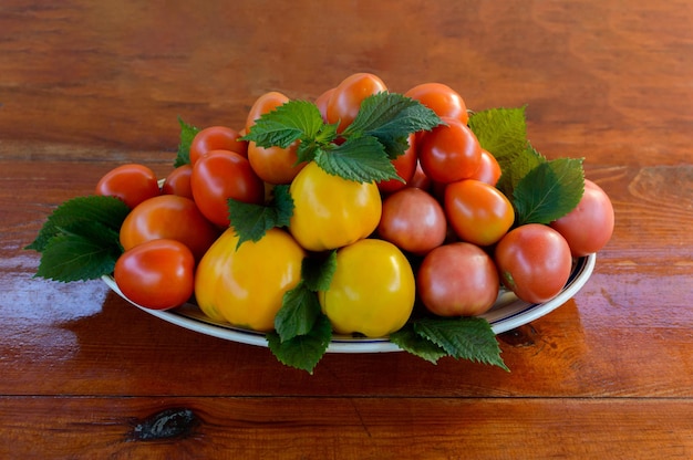 Verse tomaten in een bord op een houten ondergrond. Collectie van tomaten.