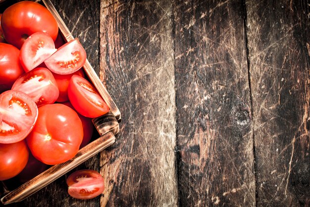 Verse tomaten in een oude doos. Op een houten achtergrond.