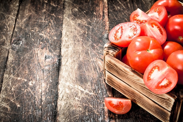 Verse tomaten in een oude doos. Op een houten achtergrond.