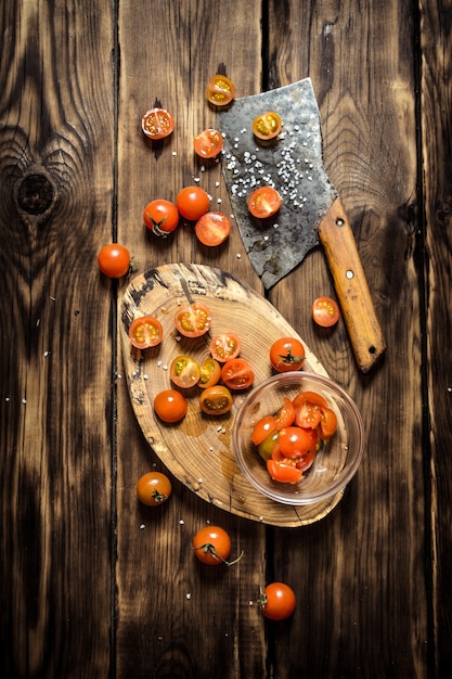 Verse tomaten met een bijl voor snijden op houten tafel.