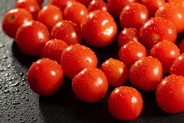 Verse tomaten met waterdruppels op zwarte keukentafel