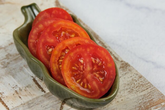 verse tomatensnij in een groene schaal op witte achtergrond