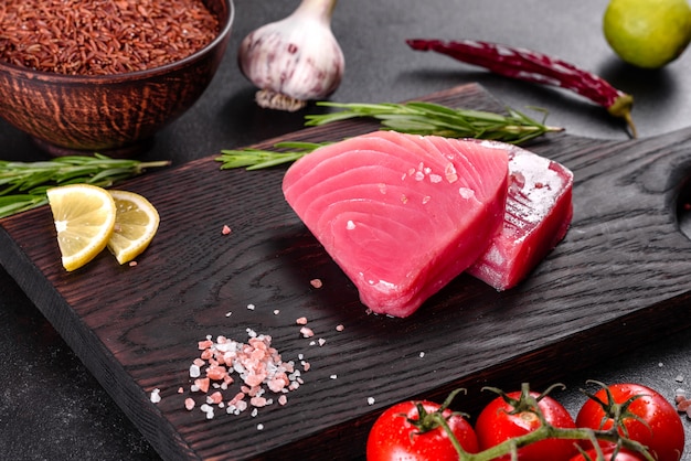 Verse tonijnfilet steaks met specerijen en kruiden op een zwarte achtergrond