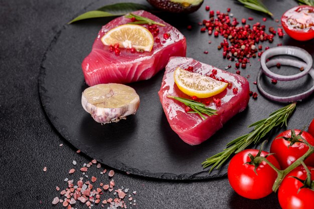 Verse tonijnfilet steaks met specerijen en kruiden op een zwarte achtergrond