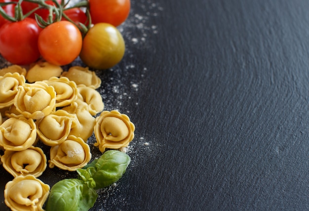 Verse tortellini met tomaten van de basilicumadvertentie op een donkere raad sluit omhoog met exemplaarruimte