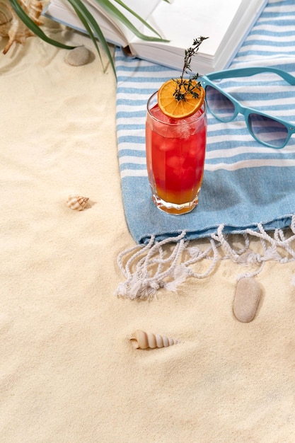 Verse tropische roodgele cocktail met schijfje sinaasappel op strand met wit zand zomervakantie op zee en reisconcept exotische zomerdrankjes