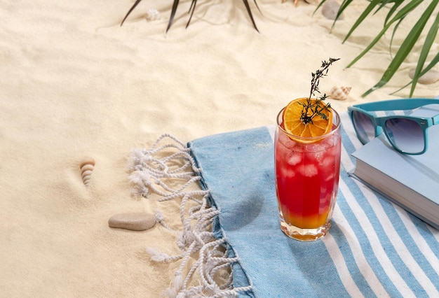 Verse tropische roodgele cocktail met schijfje sinaasappel op strand met wit zand Zomervakantie op zee en reisconcept Exotische zomerdrankjes