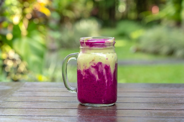 Verse tropische smoothie met rode drakenfruit, groene avocado, yoghurt en honing in glazen mok voor ontbijt, close-up
