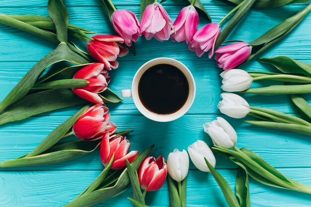 Verse tulpen rond een kopje koffie. moedersdag concept, bovenaanzicht.