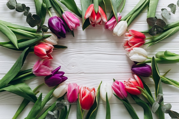 Verse tulpen rond een witte houten achtergrond. Moedersdag concept, bovenaanzicht.