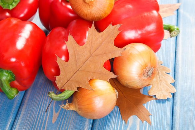 Verse uienpaprika's en herfstbladeren op planken gezonde voeding en seizoensconcept