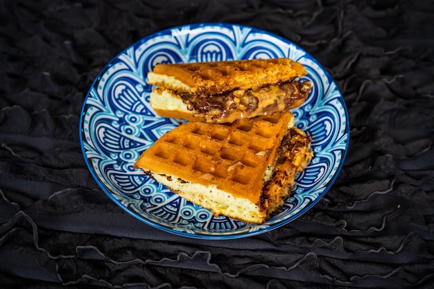 Verse wafels met pindakaas en chocolade op een versierd bord