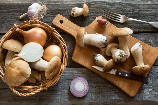 Verse witte champignons in de mand en ingrediënten voor mushroom's room-soep op een houten bord.