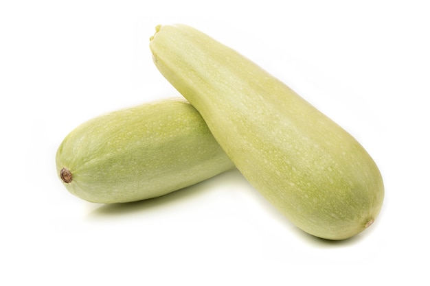 Verse witte courgette met gesneden stukjes op een witte achtergrond.