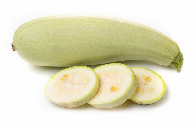 Verse witte courgette met gesneden stukjes op een witte achtergrond.