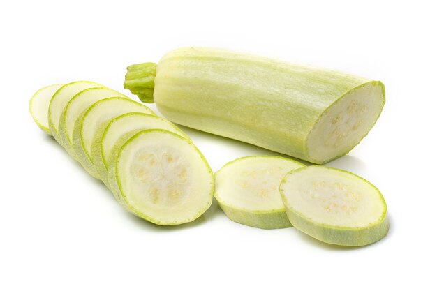 Verse witte courgette met gesneden stukjes op een witte achtergrond.