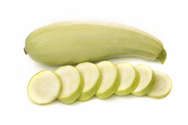 Verse witte courgette met gesneden stukjes op een witte achtergrond.