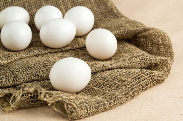 Verse witte eieren op jutetextiel bij rustieke achtergrond