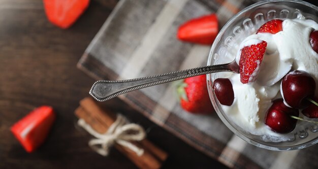 Verse yoghurt met bessen. Roomijs in een kom met verse en sappige aardbeien en kersen. Dessert met rode bessen.