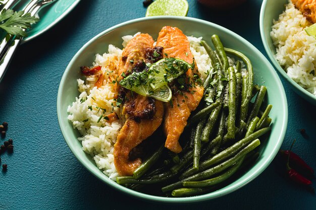 verse zalm gebakken met gember en knoflook in kokosmelk, met basmatirijst en sperziebonen in platen op tafel. gezond recept voor het hele gezin.