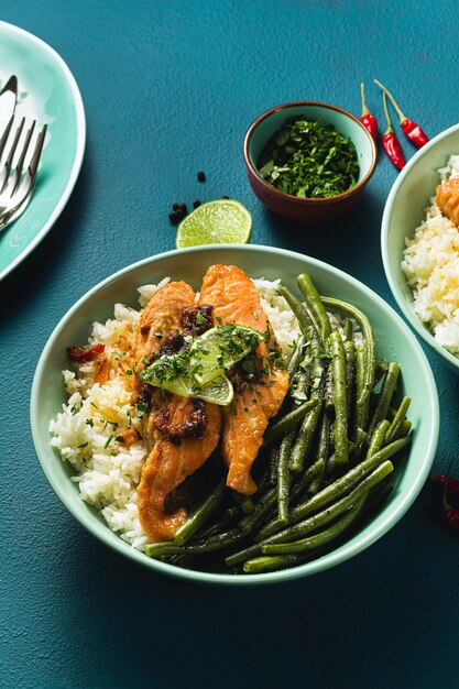 verse zalm gebakken met gember en knoflook in kokosmelk, met basmatirijst en sperziebonen in platen op tafel. gezond recept voor het hele gezin.