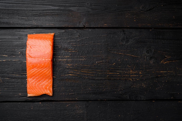 Verse zalm steak set, op zwarte houten tafel achtergrond, bovenaanzicht plat lag, met kopieerruimte voor tekst