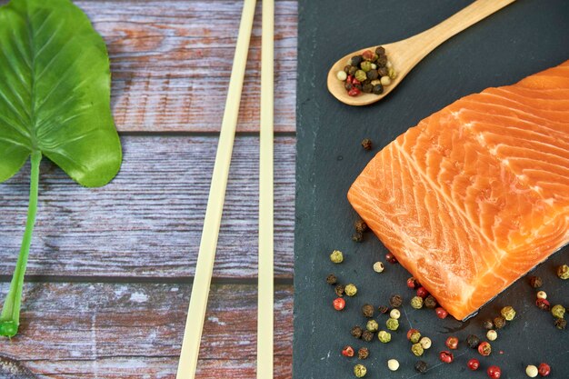 Verse zalmfilets op zwarte snijplank met kruiden en specerijen