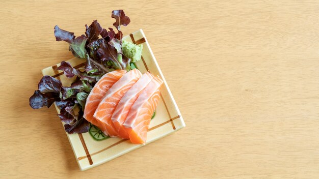 Verse zalmsashimi op een houten lijst.