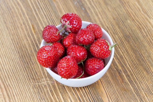 Verse zelfgemaakte aardbei liggend in een kom op een houten bord