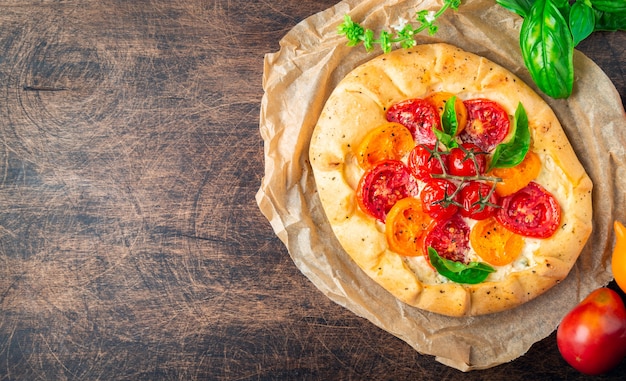 Verse zelfgemaakte galette met tomaten ricotta kaas en basilicum op rustieke multiplex achtergrond