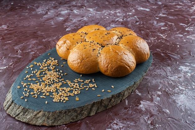 Verse zelfgemaakte hamburgerbroodjes met zwarte sesamzaadjes op houten dienblad