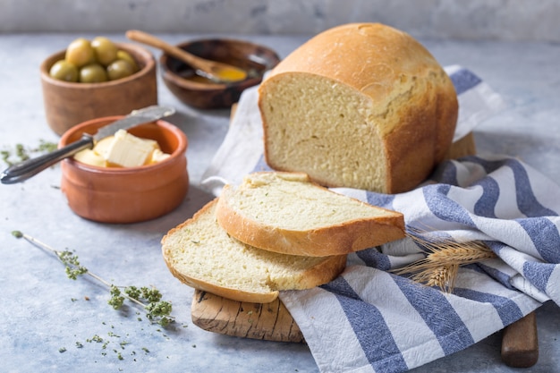 Verse zelfgemaakte krokante brood en plakjes met olijfolie, boter en groene olijven, bovenaanzicht. Bakken