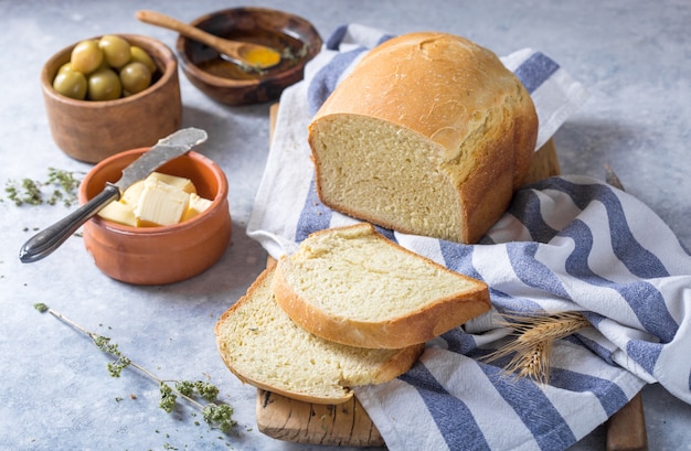 Verse zelfgemaakte krokante brood en plakjes met olijfolie, boter en groene olijven, bovenaanzicht. Bakken