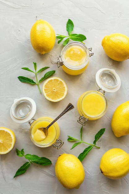 Verse zelfgemaakte lemon curd in glazen potten op lichte betonnen tafel. Bovenaanzicht.