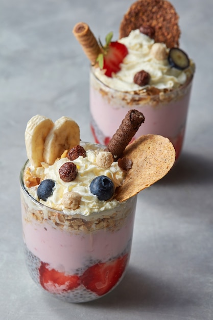 Verse zelfgemaakte muesli, bessen en yoghurt in een glas op een stenen achtergrond. Gezond ontbijt