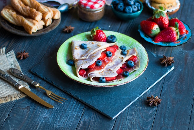 Verse zelfgemaakte pannenkoeken geserveerd op een bord met aardbeien en bosbessen