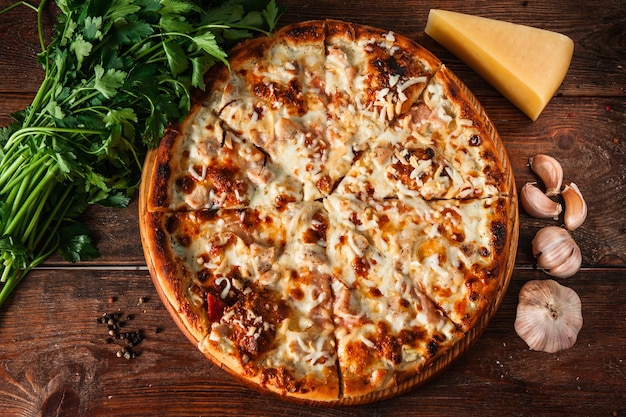 Verse zelfgemaakte pizza geserveerd op houten tafel met ingrediënten bovenaanzicht.