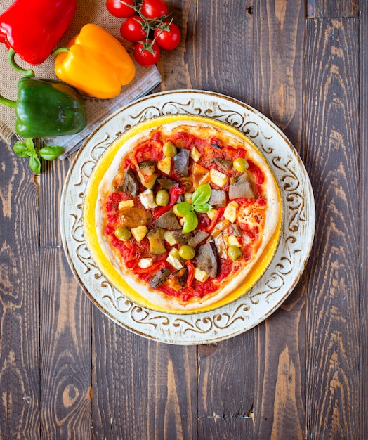 Verse zelfgemaakte pizza met verschillende groenten op een houten tafel