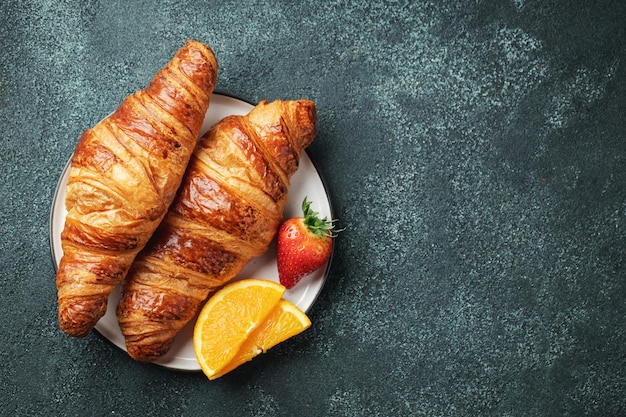 Verse zoete croissants met boter en sinaasappeljam voor het ontbijt Continentaal ontbijt op een zwarte betonnen tafel Bovenaanzicht met kopieerruimte Plat leggen