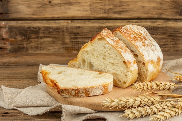 Versgebakken brood met tarweoren, geurige stukjes op een snijplank. Vintage houten planken tafel, kant-en-klaar gebakken goederen, kopieer ruimte