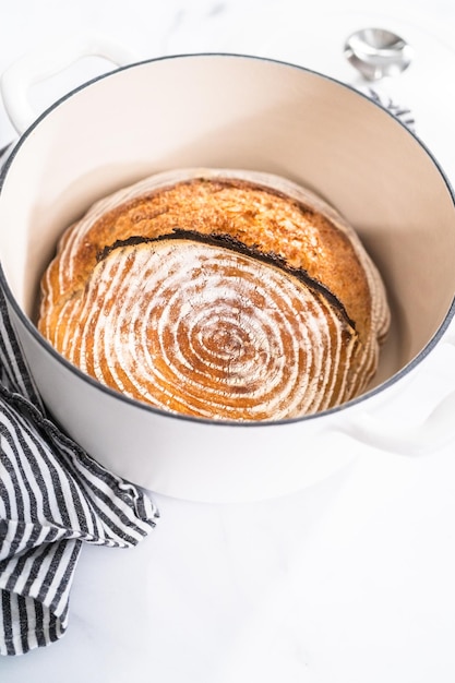 Versgebakken brood van een tarwezuurdesembrood met merktekens van broodrijsmand in geëmailleerde gietijzeren Nederlandse oven