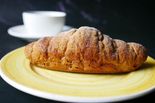 Versgebakken croissant op bord en kopje thee