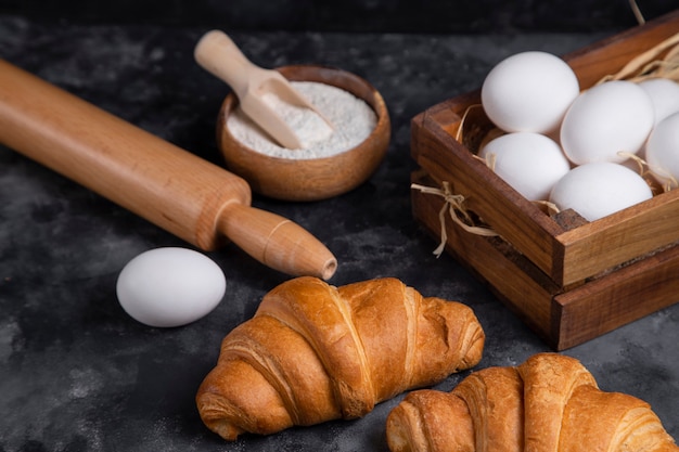 Versgebakken croissants met kippeneieren en keukengerei.