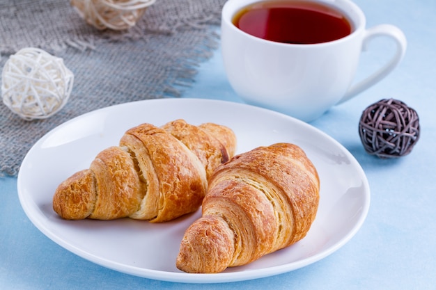 Versgebakken croissants op een bord en een kop warme thee voor Frans ontbijt