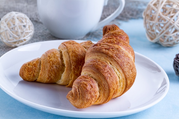 Versgebakken croissants op een bord en een kop warme thee voor Frans ontbijt