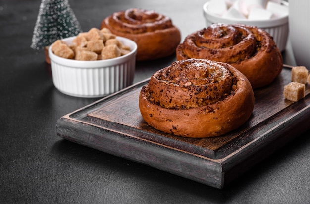 Versgebakken kaneelbroodje met kruiden en cacaovulling op een zwarte achtergrond. Kaneelbroodjes. Zweeds ontbijt.